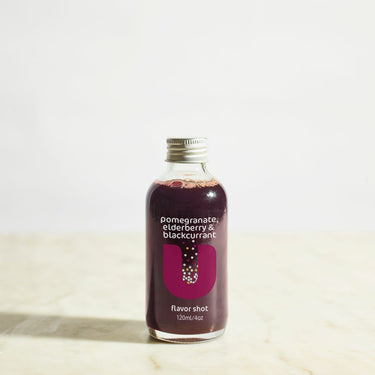 Bottle of pomegranate, elderberry, and blackcurrant flavor shot on a light background