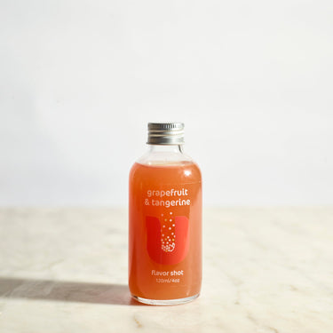 Bottle of grapefruit and tangerine flavor shot on a light background