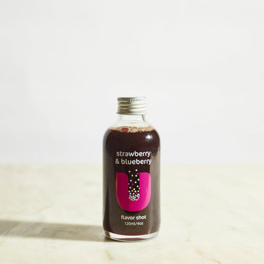 Bottle of strawberry & blueberry flavored shot on a light background